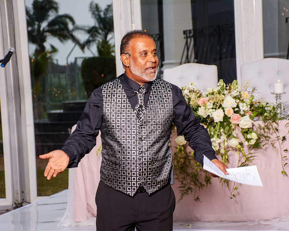 Nichal Sarawan addressing guests on the microphone at a wedding reception